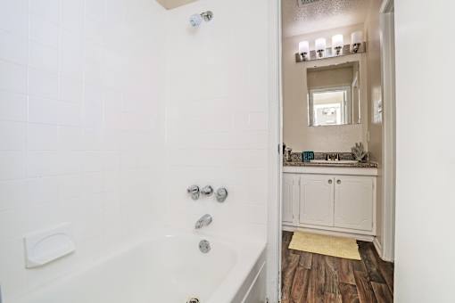 A white bathroom with a tub and a mirror at The Drake in Bossier City, LA