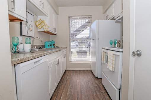 A kitchen with white appliances and wooden floors at The Drake in Bossier City, LA