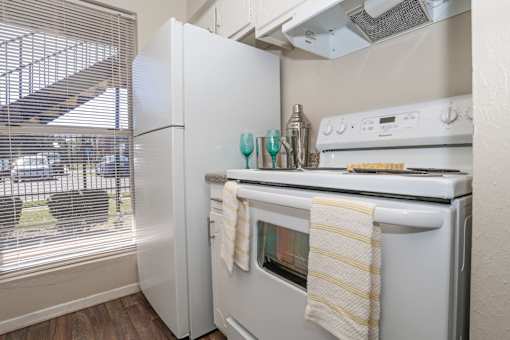 A white refrigerator and stovetop oven in a kitchen with a window at The Drake in Bossier City, LA