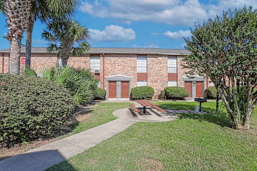 A brick apartment building with a red door and a barbeque area in front of it at Magnolia Apartments in Shreveport, LA