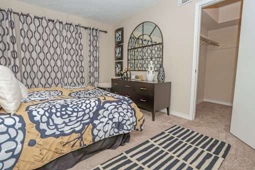Furnished model apartment bedroom with a bed, nightstand, and a rug at Magnolia Apartments in Shreveport, LA