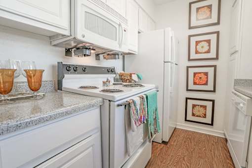 Furnished model apartment kitchen with a stove top oven and a microwave above it at Magnolia Apartments in Shreveport, LA