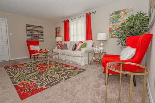 Furnished model apartment with white and red furniture and a floral rug at Magnolia apartments in Shreveport, LA