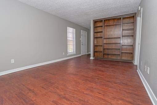 Unfurnished apartment living room with wooden floors and wooden built-in shelving at Magnolia apartments in Shreveport, LA