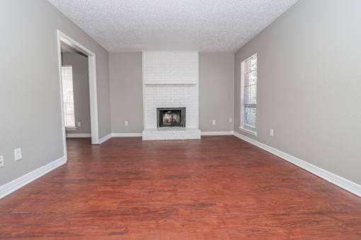A living room with a fireplace and wood flooring at Magnolia Apartments in Shreveport, LA