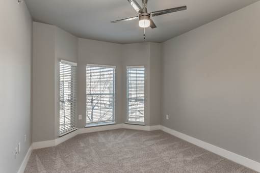 A2 model bedroom with carpeted floors, ceiling fan and bay window at Asheville at Spring Branch apartments in Houston, TX