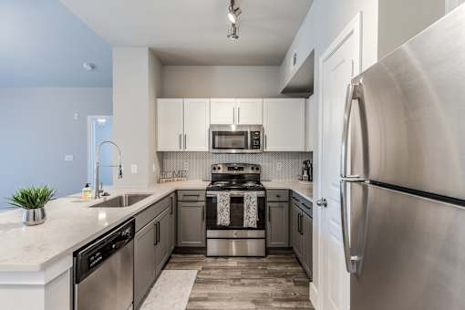 A2 model kitchen with stainless steel appliances, quartz counters, and white cabinets at Asheville at Spring Branch apartments in Houston, TX