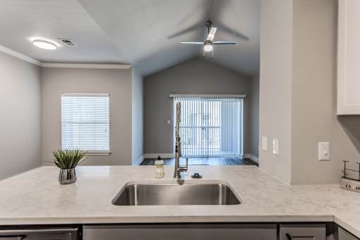 A2 model kitchen sink and quartz counter looking over to living room at Asheville at Spring Branch apartments in Houston, TX