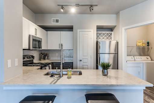 A2 model kitchen with quartz countertops and stainless steel appliances at Asheville at Spring Branch apartments in Houston, TX
