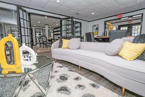 Modern resident lounge in leasing office with a grey sofa and a glass coffee table at Maplewood apartments in Shreveport, LA.