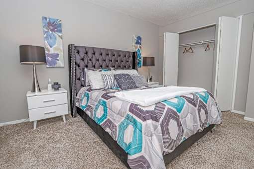 Model bedroom with a large bed and a white nightstand at Maplewood apartments in Shreveport, LA.