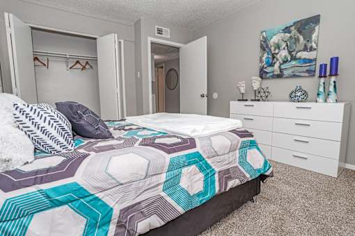 Model bedroom with a bed, dresser, and closet at Maplewood apartments in Shreveport, LA.