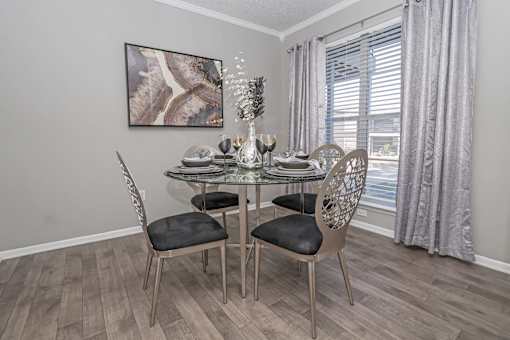 Dining room with table and 4 chairs and a large window filling space with sunlight at Maplewood apartments in Shreveport, LA.