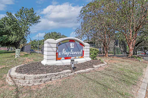 A sign for Maplewood is displayed in a landscaped area at Maplewood apartments in Shreveport, LA.