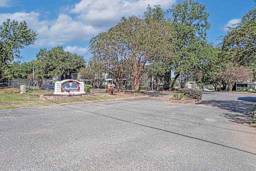 Property signage that says Maplewood with pretty trees and landscaping at Maplewood apartments in Shreveport, LA.