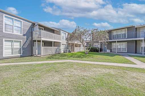 A sunny day at the apartment complex with apartment buildings on the left and right and a walkway in front at Maplewood apartments in Shreveport, LA.