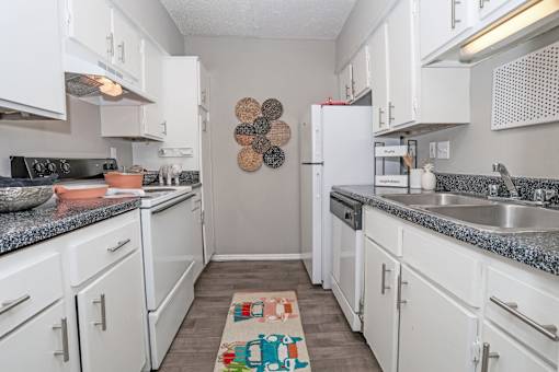 A kitchen with white cabinets and a grey counter top at Maplewood apartments in Shreveport, LA..