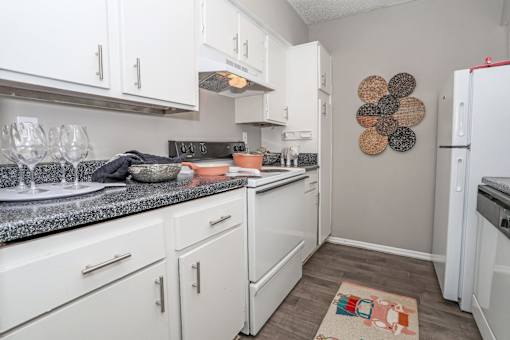 A kitchen with white cabinets and a gray counter top at Maplewood apartments in Shreveport, LA.