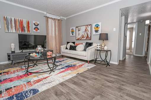 Model living room with a white couch and a glass coffee table at Maplewood apartments in Shreveport, LA.