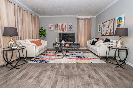 Model apartment living room with two white couches, a coffee table, and a rug at Maplewood apartments in Shreveport, LA.