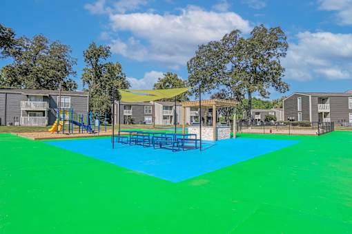 Picnic and BBQ area in blue and green surface and a yellow canopy at Maplewood apartments in Shreveport, LA.