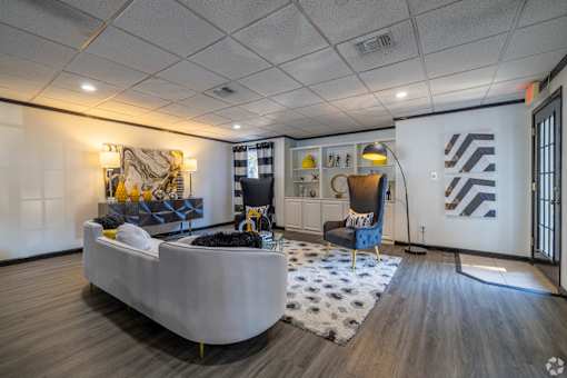 Cozy lounge in leasing office with a grey sofa and a patterned rug at Maplewood apartments in Shreveport, LA.