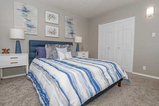 A bedroom with a bed, nightstand, and two lamps at The Oasis apartments in Bossier City, LA