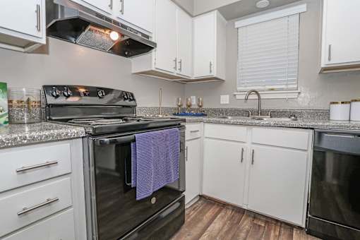 A kitchen with a black oven and white cabinets in our model at The Oasis apartments in Bossier City, LA