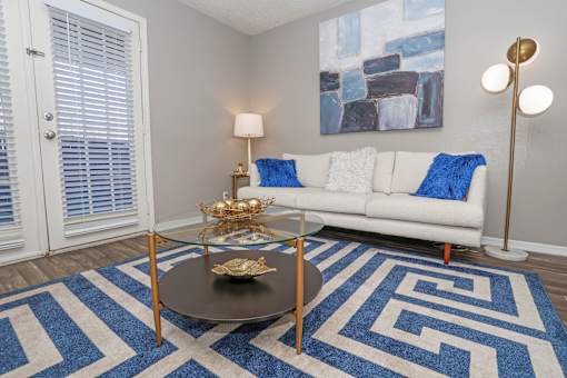 Spacious living room with pattern rug and off white couch at The Oasis apartments in Bossier City, LA