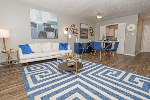 Model living room and dining area with couch and rug at The Oasis apartments in Bossier City, LA