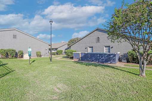 A grassy area in front of a building with a pet waste station at The Oasis apartments in Bossier City, LA
