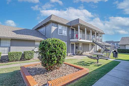 Apartment building with picnic table in front and lush greenery at The Oasis apartments in Bossier City, LA