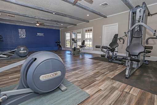 A gym with a blue wall and a variety of exercise equipment at The Oasis apartments in Bossier City, LA
