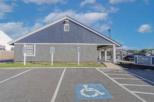 Parking lot with a handicap parking space in front of the leasing office at The Oasis apartments in Bossier City, LA