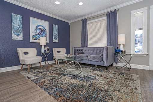 Interior of leasing office with a grey couch, two chairs, and a rug at The Oasis apartments in Bossier City, LA