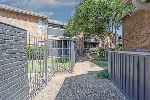 A gravel path leads to a gated entrance.
