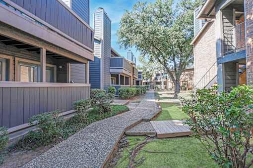 Walkways in between apartments with lush landscaping at The Pearl apartments in Shreveport, LA