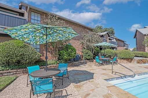 Poolside seating with shaded tables and chairs at The Pearl apartments in Shreveport, LA