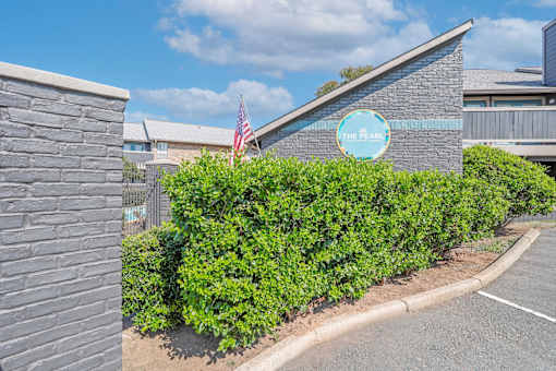 A building with a sign that says "The Pearl" is surrounded by green bushes.