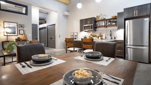 A modern kitchen with a dining table set for two.