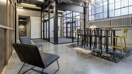 A black chair is in the foreground of a room with a table and chairs in the background.