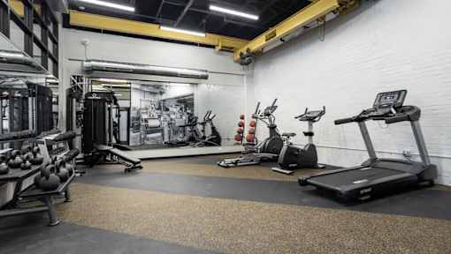 A gym with a variety of equipment including treadmills, weights, and exercise machines.