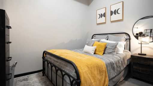 A bedroom with a bed, nightstand, and two framed pictures on the wall.