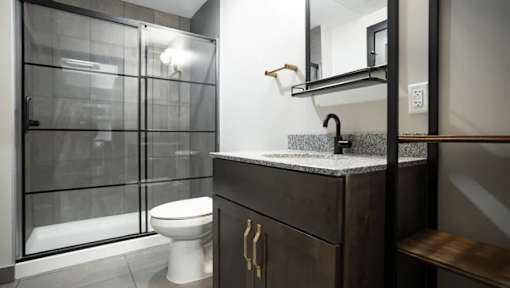 A modern bathroom with a white toilet and a dark wood vanity.