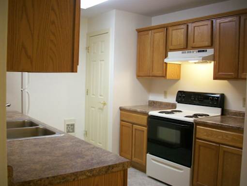 A kitchen with a sink, stove, and cabinets.