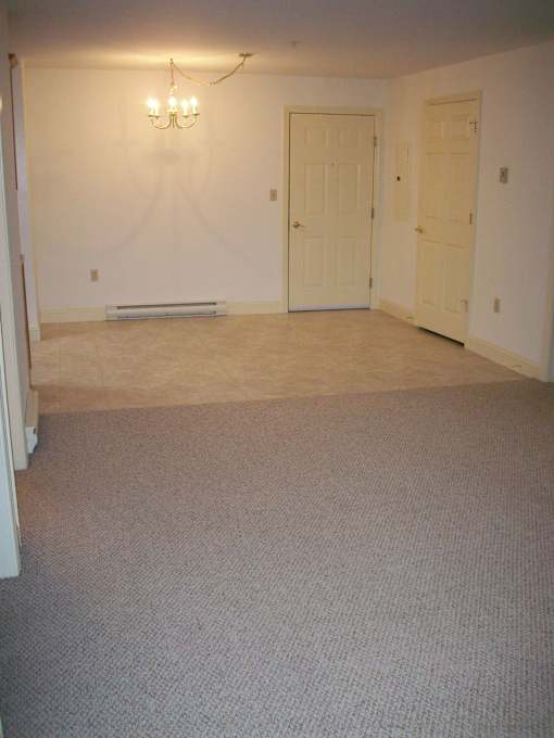 A room with a chandelier, two doors, and a carpeted floor.