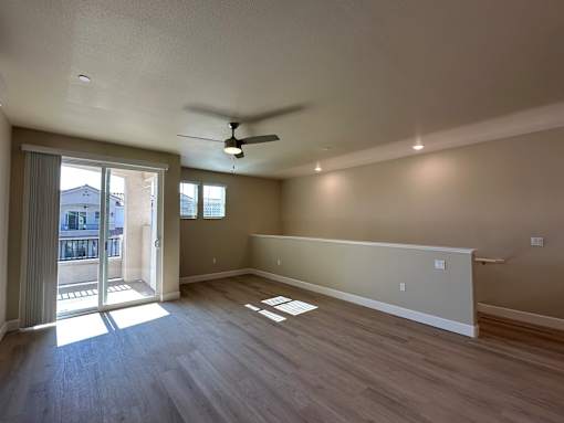 A room with a ceiling fan and sliding glass doors.