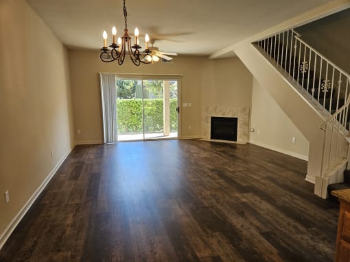 an empty living room with a fireplace and a chandelier
