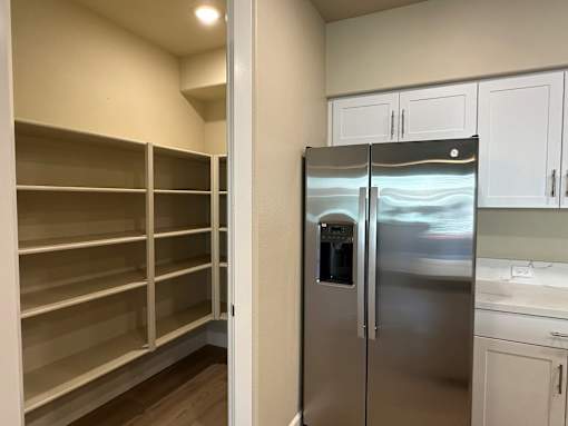A kitchen with a refrigerator and empty shelves.