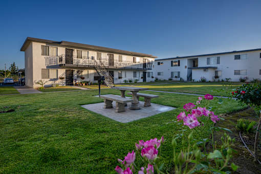 A building with a balcony and a patio table surrounded by flowers.